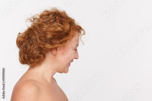 Profile of happy mature woman looking down while posing isolated on white in studio. Red haired lady smiling. Emotions concept.
