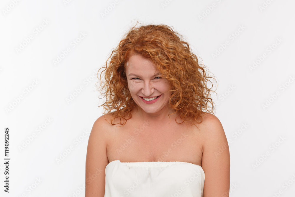 Spiting mature woman posing isolated onwhite background. Beautiful red haired woman looking at camera in studio. Spiting mature woman posing isolated onwhite background. Beautiful red haired woman looking at camera in studio.