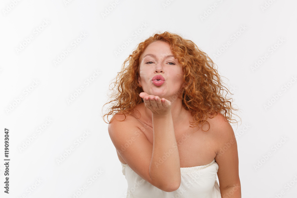 Picture of charming mature woman giving kisses to someone while posing in studio. Red haired lady in white dress expressing emotions. Picture of charming mature woman giving kisses to someone while posing in studio. Red haired lady in white dress expressing emotions.