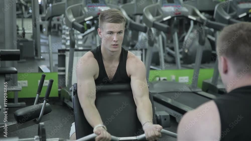 The man raises the bar in the gym The man raises the bar in the gym