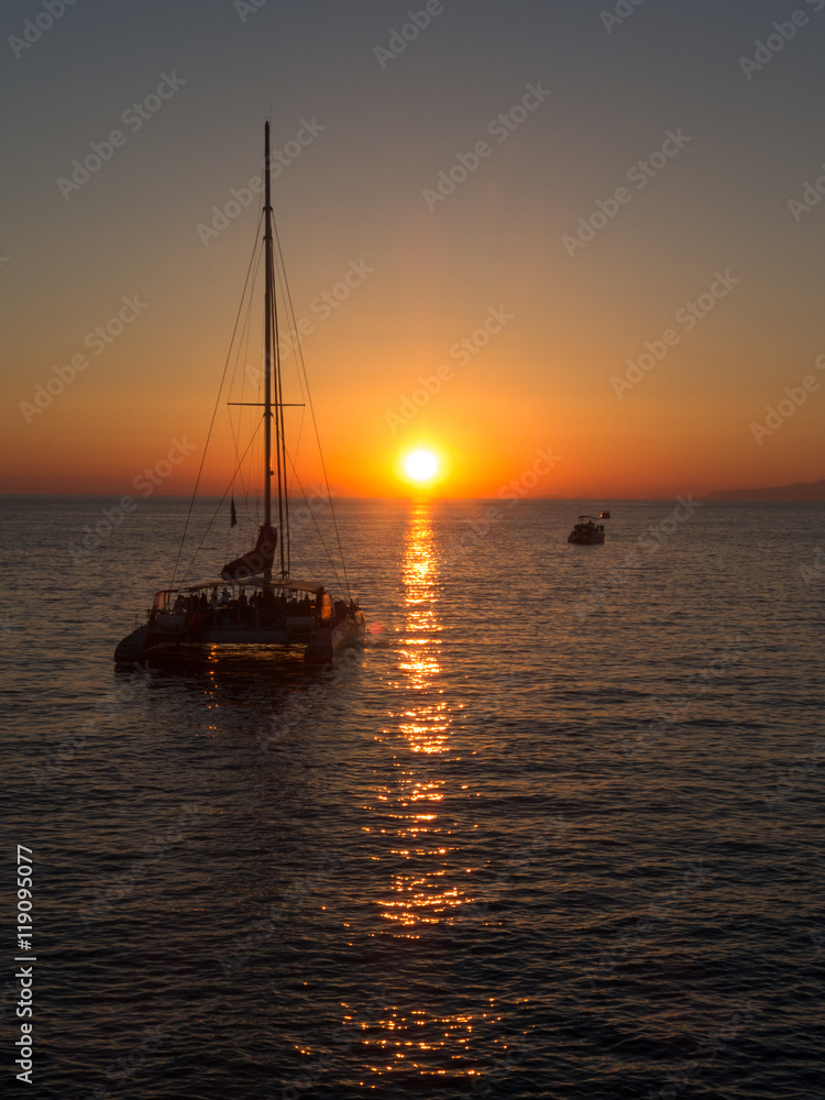 Sunset at sea with yacht on horizon - Oia, Santorini