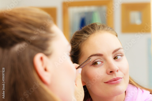 Woman tweezing eyebrows plucking with tweezers