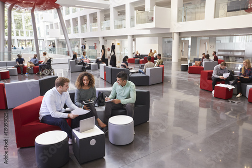 Students sitting in university atrium, three in foreground photo