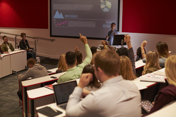 Students at university lecture raise hands to ask questions