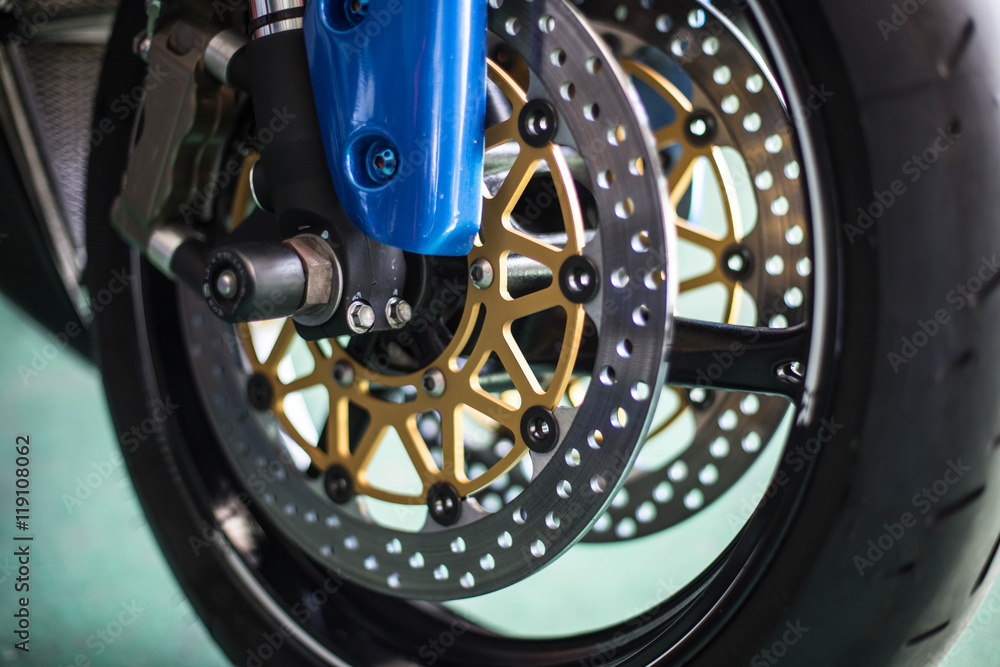 The front wheel of a motorcycle. Close up brakes and spokes