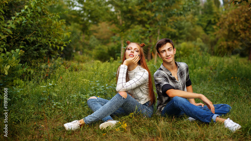 Loving couple teens sitting on the lawn. © Vagengeim
