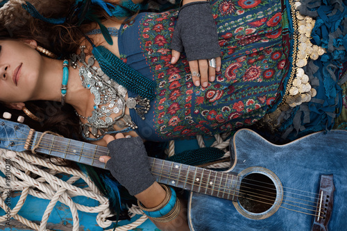 Atrractive young hippie woman with guitar outdoors