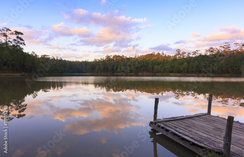Beautiful natural view of serene lake in sunset with a wooden dock beside the lake.
