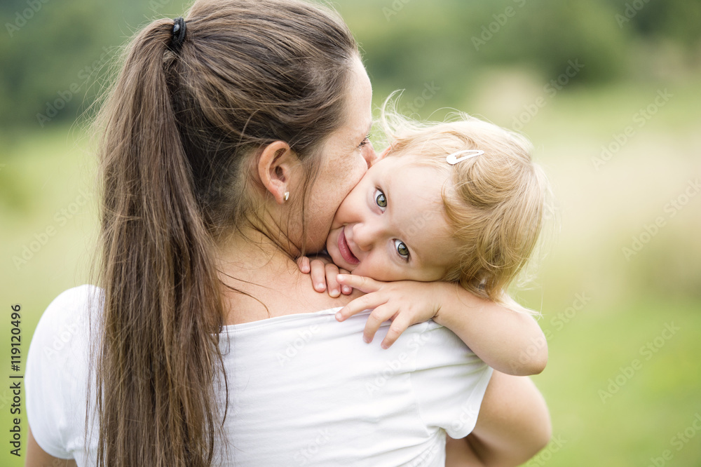 Mother kissing at hugging her little daughter Mother kissing at hugging her little daughter