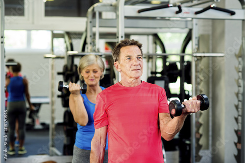 Senior man and mature woman working out in fitness gym photo