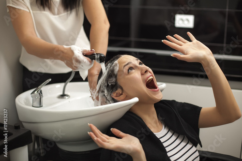 scared young woman in a hair salon while washing her hair