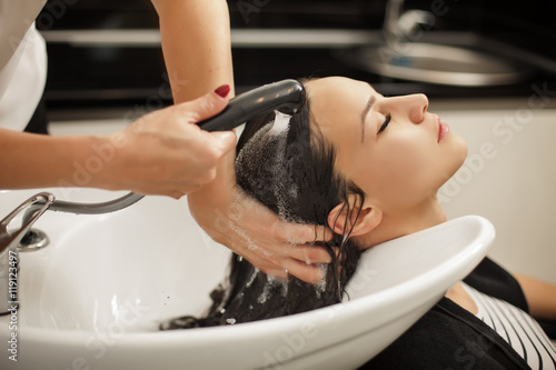 young woman in a hair salon enjoys washing her hair