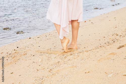 Woman legs walking on the beach sand