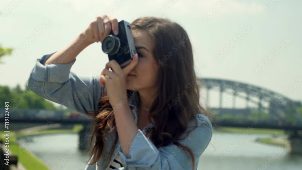 Young girl standing next to the river and doing photos on old camera
