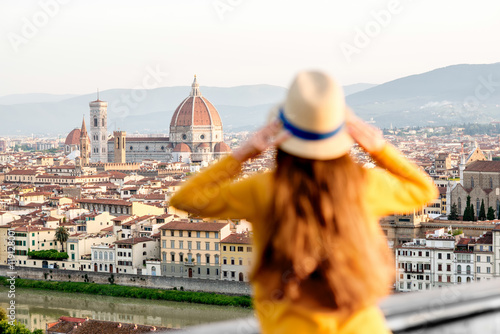 Young female tourist enjoying the view on the old town of Florence from Michelangelo square in the morning in Italy. Back focus