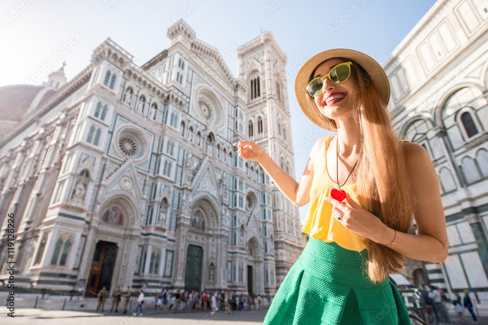 Young female traveler dressed colorful with heart pendant showing famous Santa Maria del Fiore cathedral in Florence. Promoting tourism in Italy