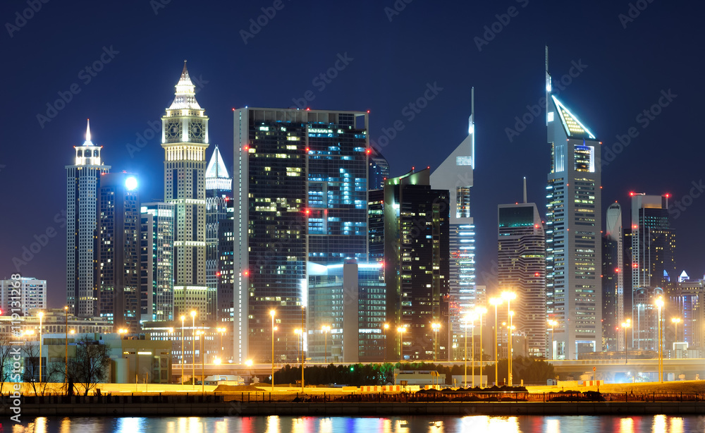 Fototapeta premium Amazing tallest skyscrapers in Sheikh Zayed road area during calm night with colorful neons. Downtown summer night skyline. Dubai, United Arab Emirates.