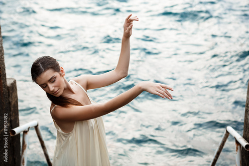 Young beautiful ballerina dancing and posing outside  sea background.