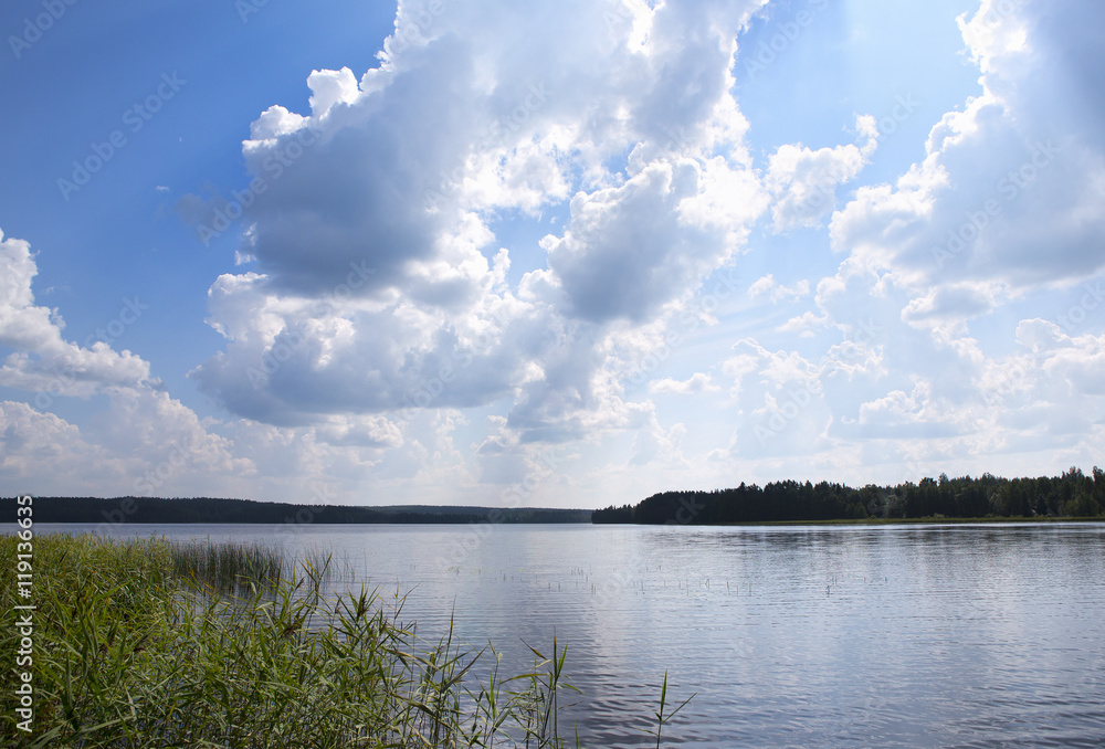 Calm before the storm. An image of dramatic clouds gathering up in the blue sky over the lake.