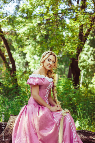 Beautiful girl with long hair braided in a braid, in corset and magnificent pink dress.