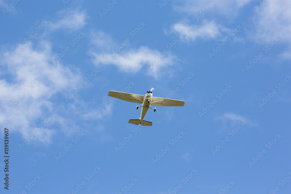 Fototapeta premium Small airplane flying above against a blue sky.
