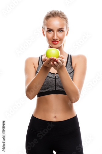Beautiful sportive girl posing, holding apple over white background. © Cookie Studio