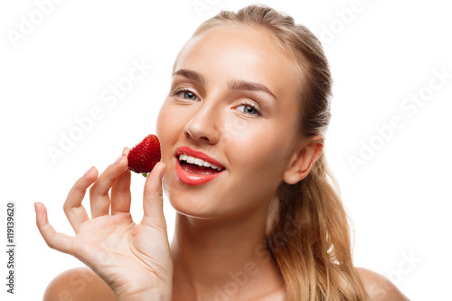 Beautiful sportive girl posing, eating strawberry over white background.