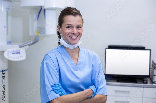 Smiling dental assistant standing with arms crossed