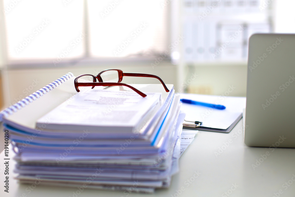 Laptop with stack of folders on table white background Laptop with stack of folders on table white background