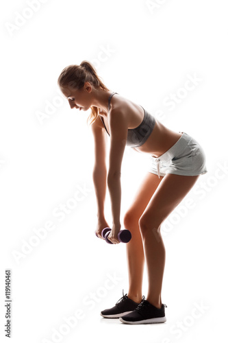 Beautiful sportive girl training with dumbbells over white background.