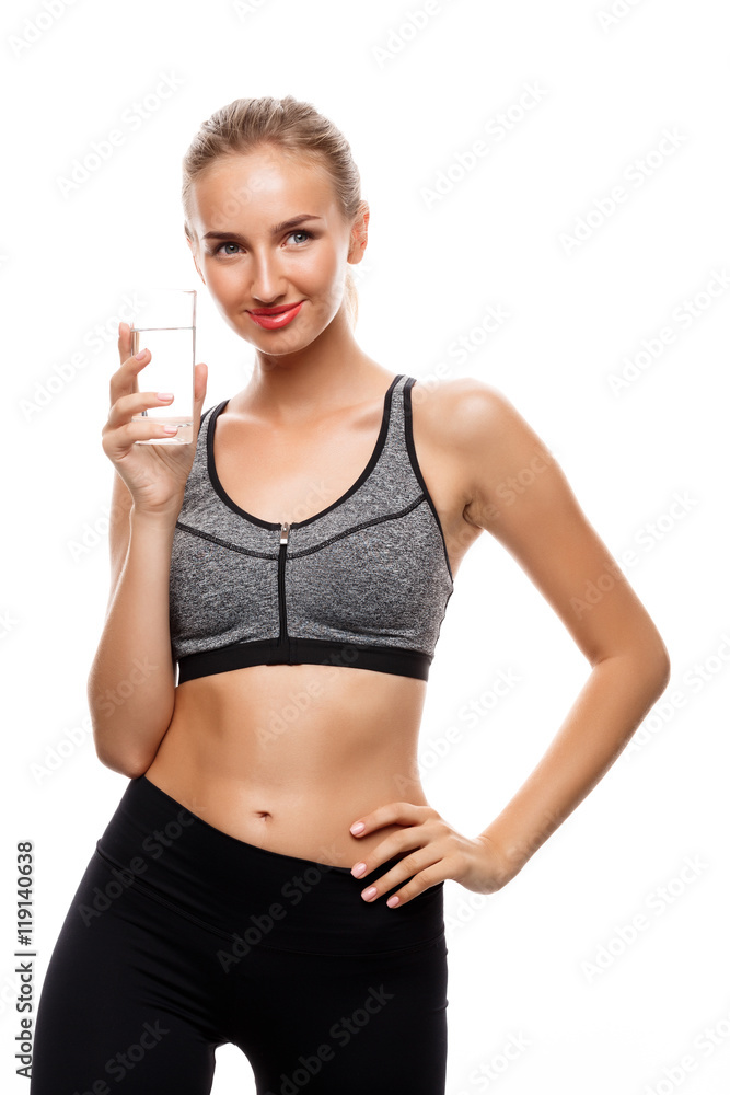Beautiful sportive girl posing, holding glass of water over white background.