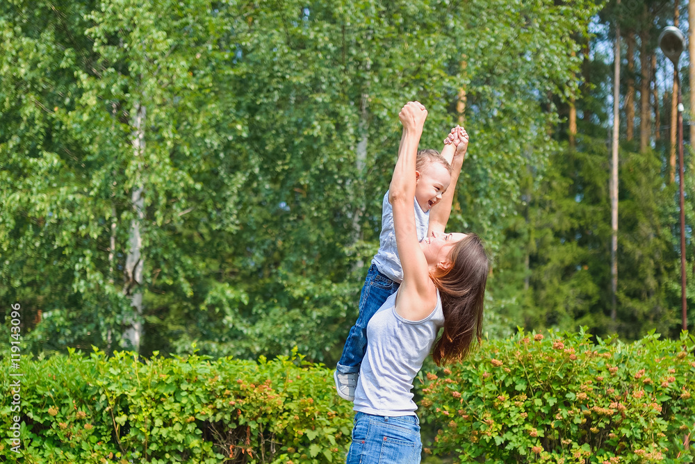 Happy family having fun outdoors. Mother holding son in the air like airplane Happy family having fun outdoors. Mother holding son in the air like airplane