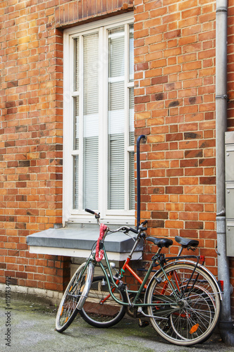 Two bicycle near the brick house window