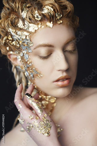 Portrait of beautiful model with shiny foil on face and hair