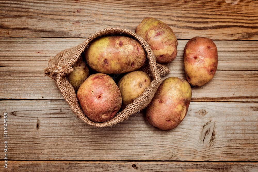 potatoes in burlap sack on rustic wooden table, top view potatoes in burlap sack on rustic wooden table, top view