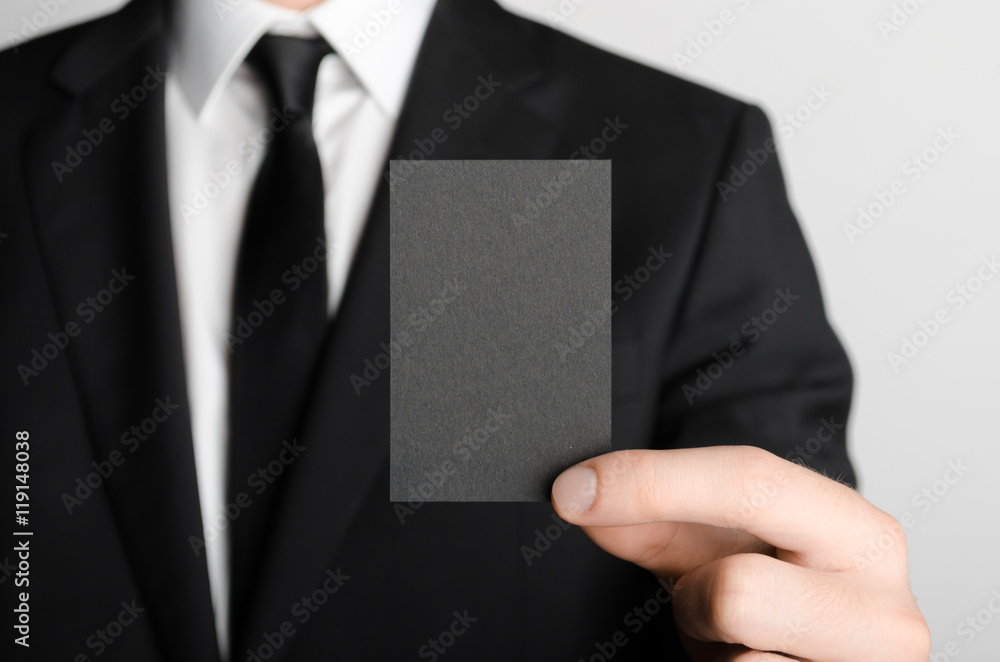 Black Business Card Mock-Up (85x55mm) - Man in a black suit holding a black card on a gray background. Black Business Card Mock-Up (85x55mm) - Man in a black suit holding a black card on a gray background.