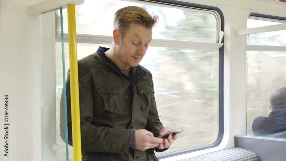 Mature man standing on a train. He is typing on his smart phone. Mature man standing on a train. He is typing on his smart phone.