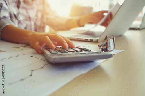 Asian Business woman using a calculator to calculate the numbers vintage tone photo