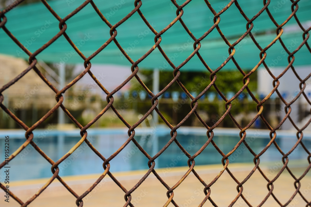 A blur picture of a swimming pool behind the wire mesh. A blur picture of a swimming pool behind the wire mesh.