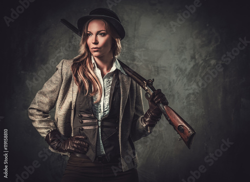 Fotografiet Lady with shotgun and hat from wild west on dark background.