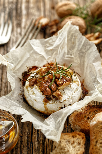 Baked Camembert with walnuts, honey  and rosemary on wooden rustic table