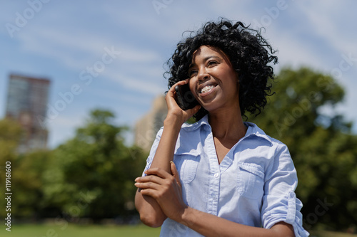 Black woman in a park talking on cell phone
