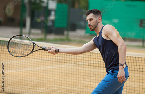 Happy young man playing on tennis clay court. © lashkhidzetim