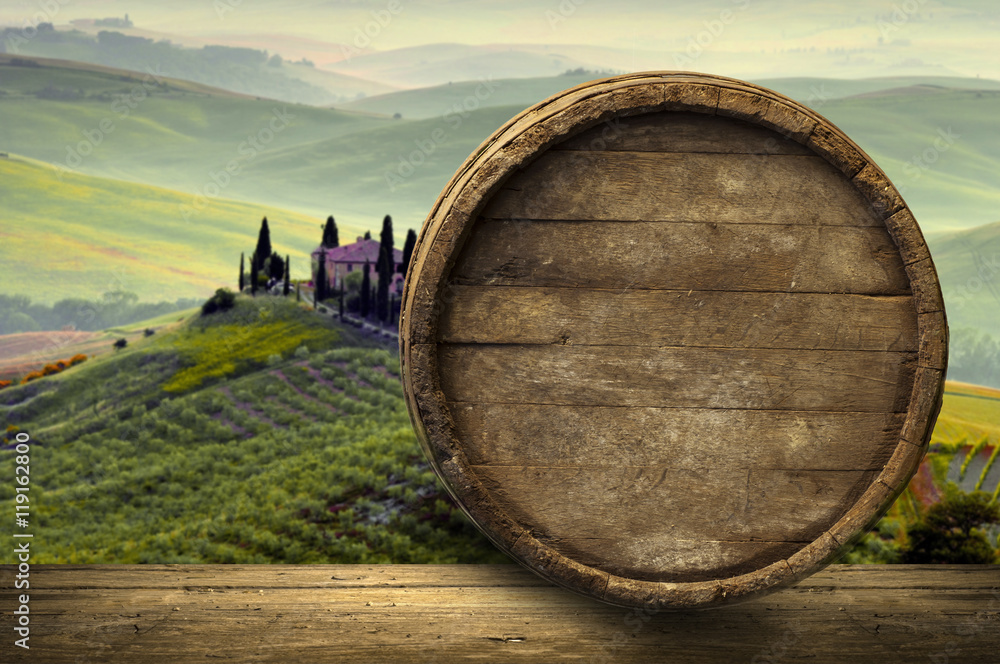 Red wine with barrel on vineyard in green Tuscany, Italy