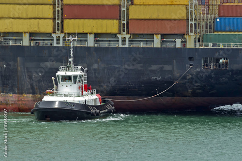 Naval tug moving a container ship