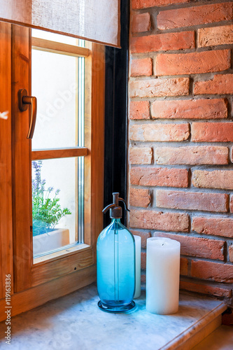 Obraz na plátně Old soda siphon and white candle on windowsill near brick wall