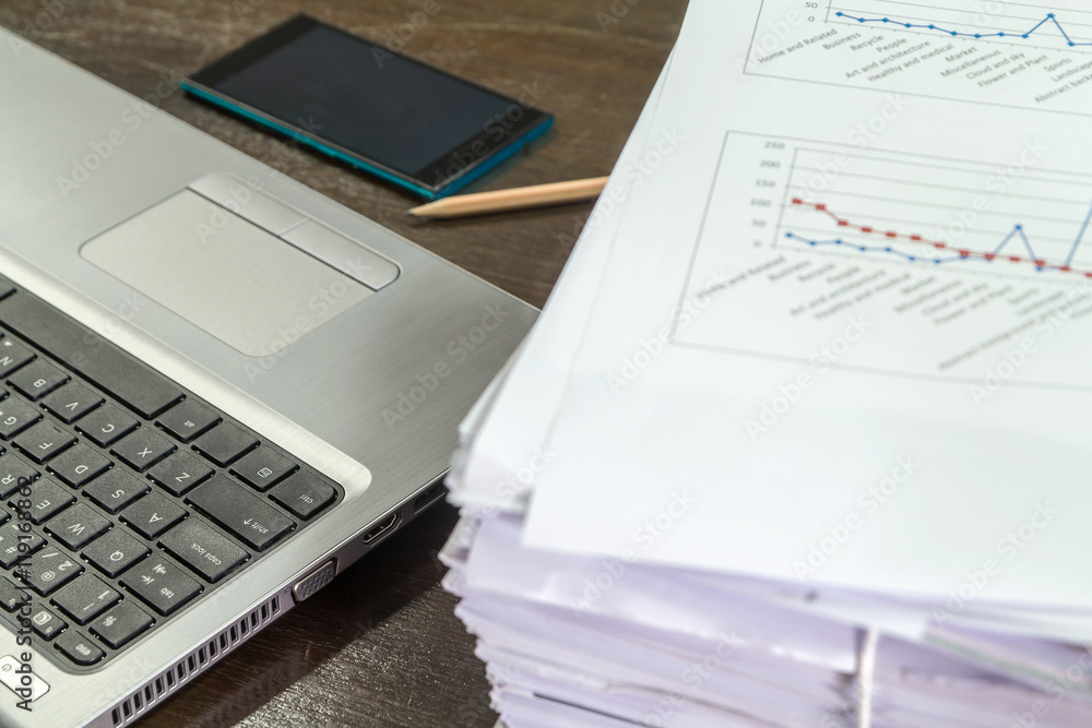 Smartphones on laptop near documents stack and pencil Smartphones on laptop near documents stack and pencil