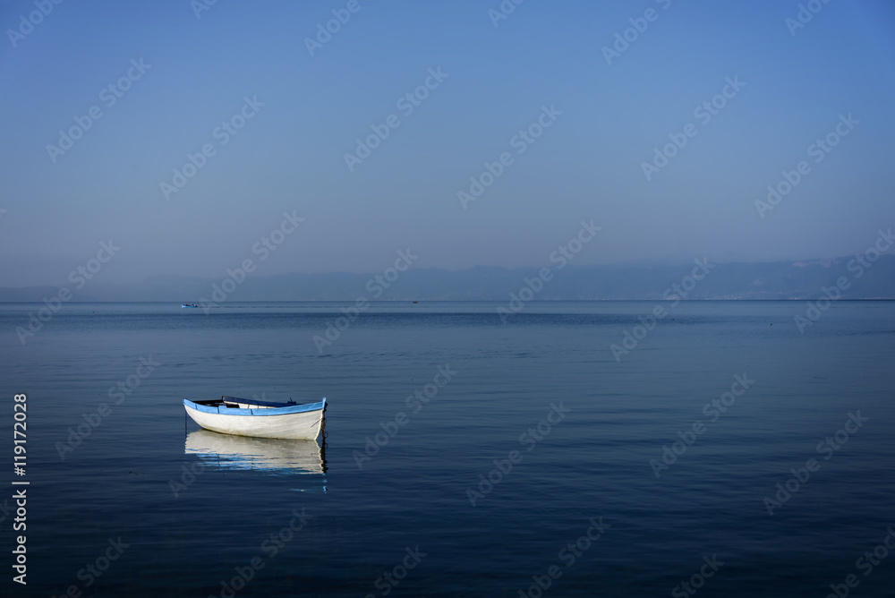 Boat on lake with a reflection in the water at sunrise Boat on lake with a reflection in the water at sunrise