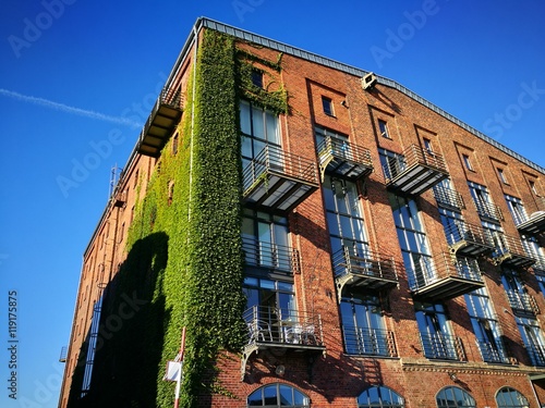 Saniertes altes Speichergebäude aus Backstein mit begrünter Fassade vor blauem Himmel im Sonnenschein am Kreativkai am alten Hafen von Münster in Westfalen im Münsterland photo