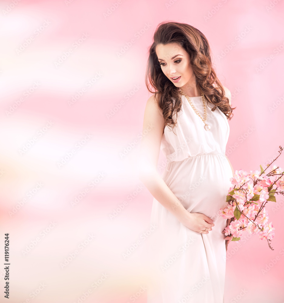 Beautiful pregnant woman holding a branch with summer flowers